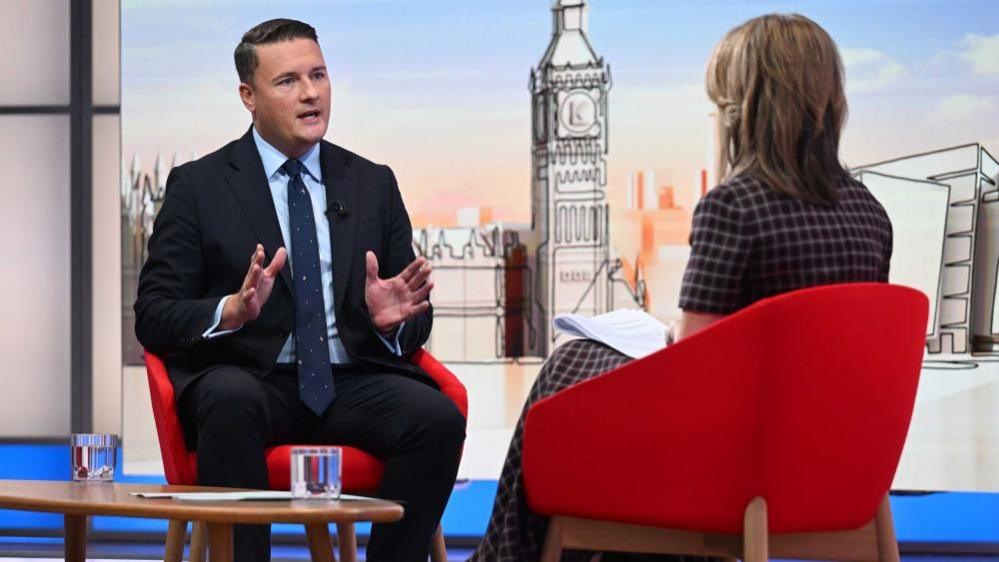 Wes Streeting in the Sunday with Laura Kuenssberg studio. He is wearing a dark navy suit and navy tie with a light blue shirt.