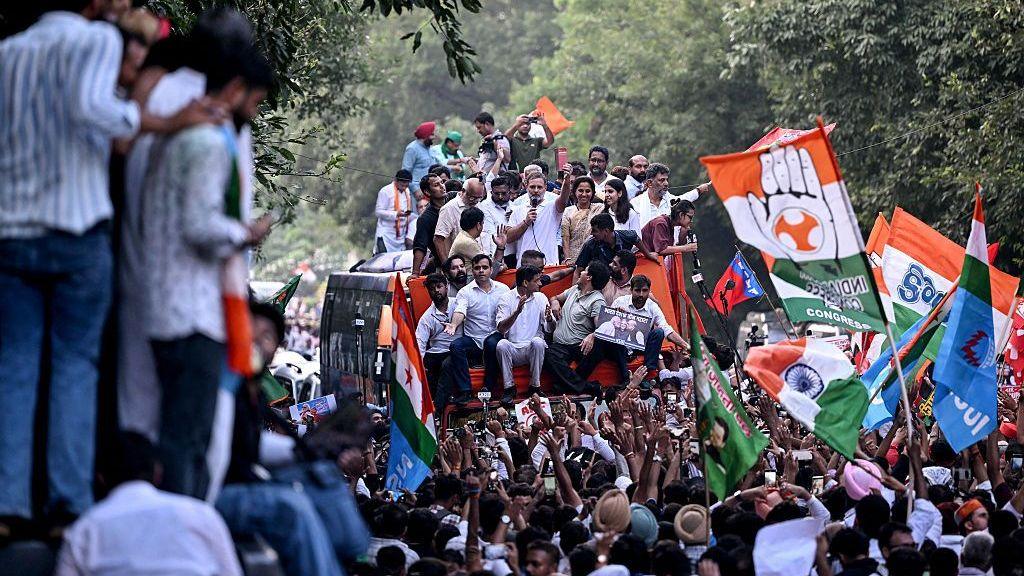 Rahul Gandhi holds a copy of 'The Constitution of India' from atop a bus during a protest march