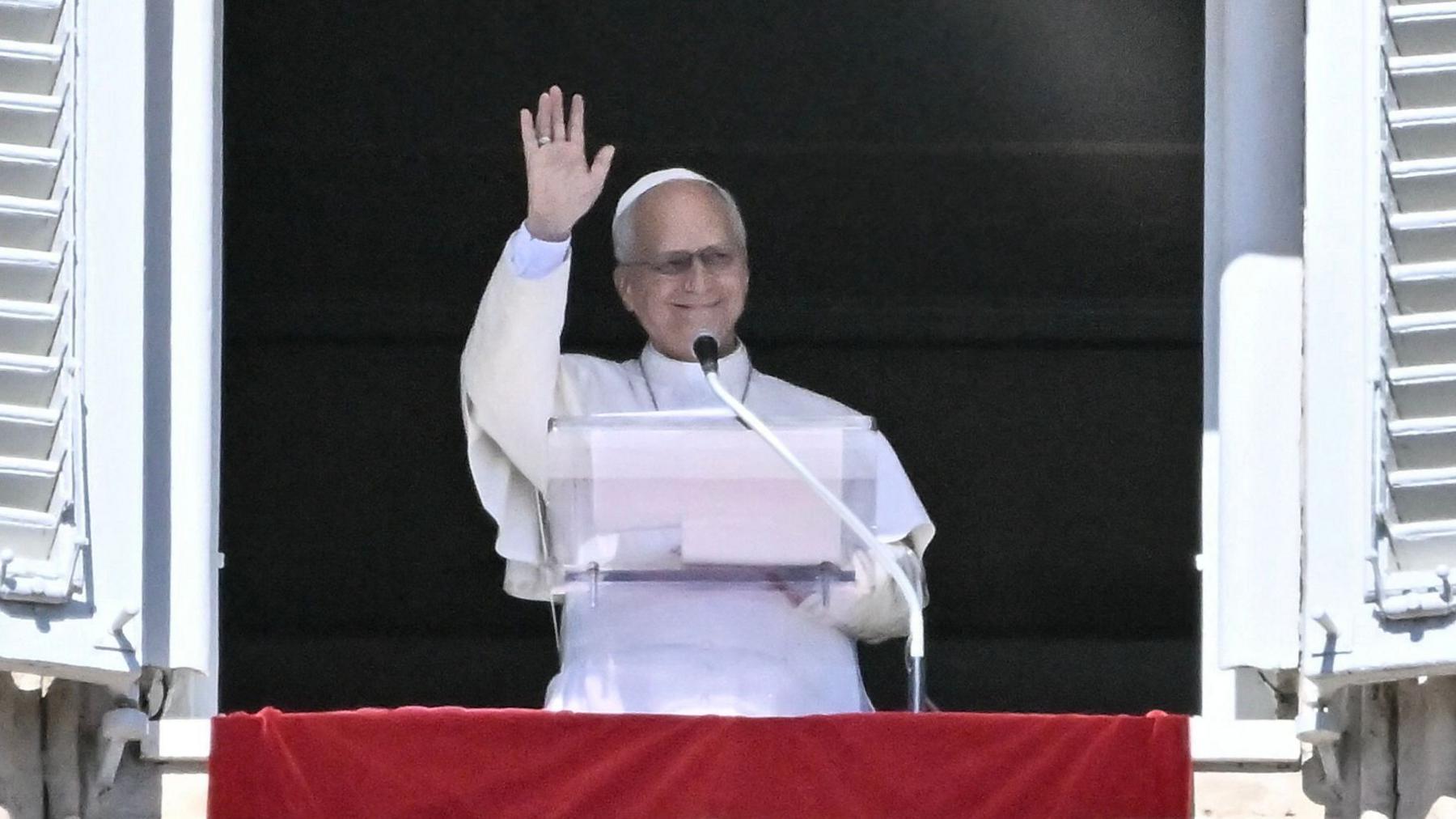 Pope Leo XIV waves from the window of his residence overlooking St Peter's Square wearing the traditional white papal cassock, mozzetta and zucchetto silk hat 