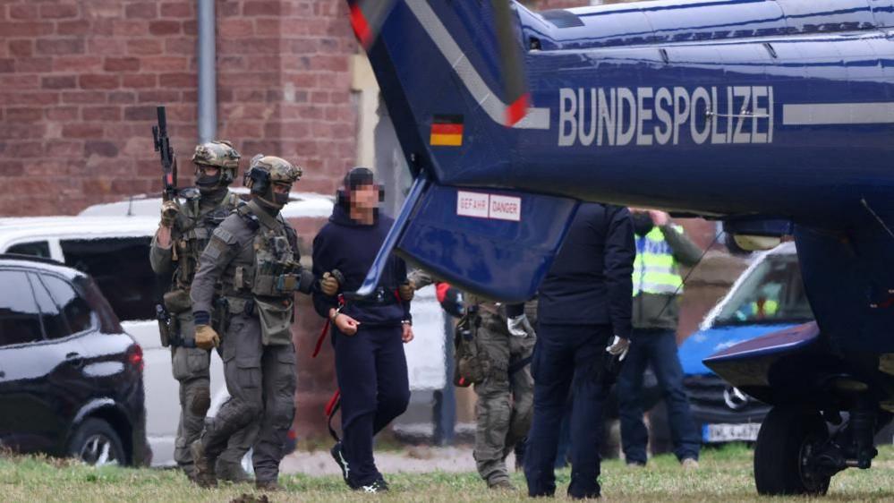Police escorts Serhii K. to a helicopter following a hearing with the German Federal Public Prosecutor, after Italy's top court approved the handover to Germany of the Ukrainian man, suspected of coordinating the 2022 sabotage of the Nord Stream gas pipeline, in Karlsruhe, German
