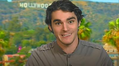 RJ Mitte sitting inside a studio with the Hollywood sign in Los Angeles behind him.