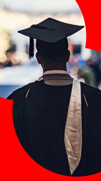 A man wearing graduation robes and a cap faces away from the camera