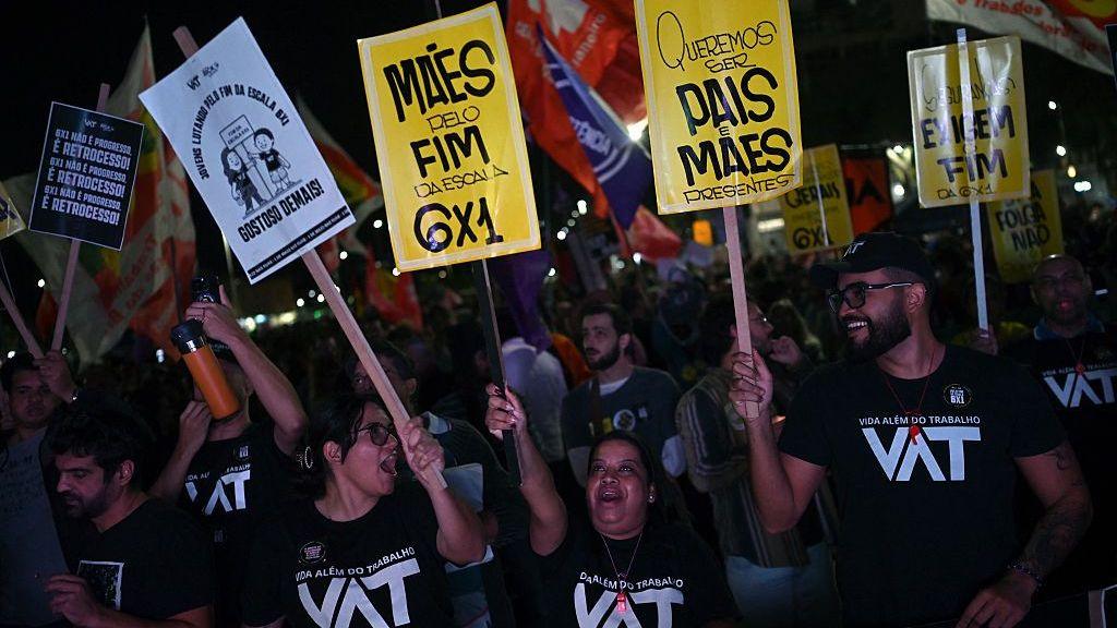 Men and women wearing black T-shirts with the letters VAT (for Vida alem do trabalho, Portuguese for Life Beyond Work) attend a demonstration calling for the end of the six-day workweek in Rio de Janeiro, on 10 July, 2025. 