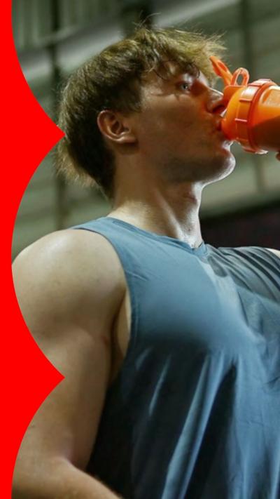 Man in vest drinking from an orange cup