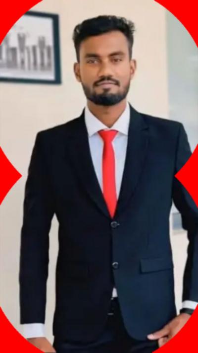 A man with short dark hair wearing a dark suit with a red tie.