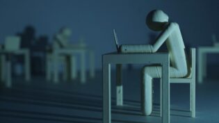 Plastic figure resembling a human who sits on a table infront of a laptop in a dark room. Long shadows disseminate a gloomy mood.