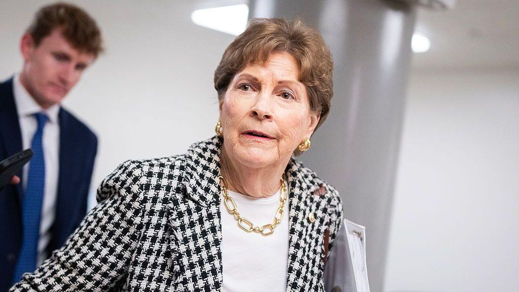 Sen. Jeanne Shaheen, who has short brown hair and is wearing a blazer with a black and white dogtooth pattern, a white top and gold jewellery, talks with reporters during votes in the US Capitol on Wednesday, September 30, 2026. 