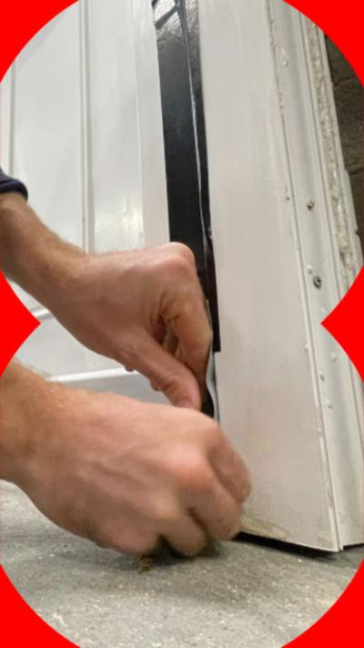 A man adding duct tape to the gaps in his white door.