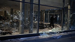 A man takes photos of a looted store after a demonstration against rising living costs, joining students' grievances, in Lyon, France, Saturday, Oct. 17, 2026