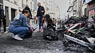 People clean up debris in a street next to burned bicycles the day after a demonstration against rising living costs and in solidarity with students' grievances, in Paris
