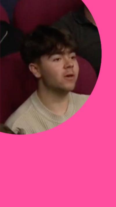 A young man with short brown hair looks at someone off-camera