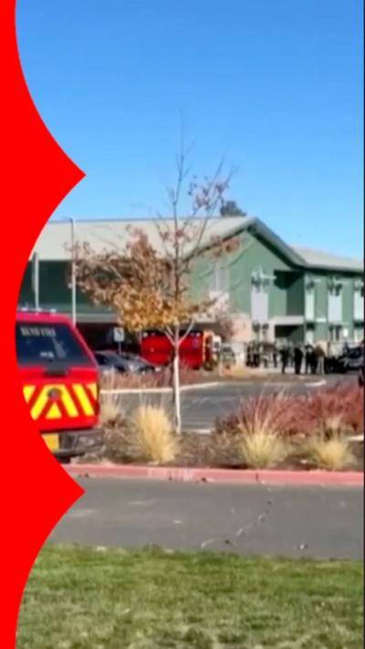 Two sheriffs stood, one with hand on car door handle, outside of a primary school.