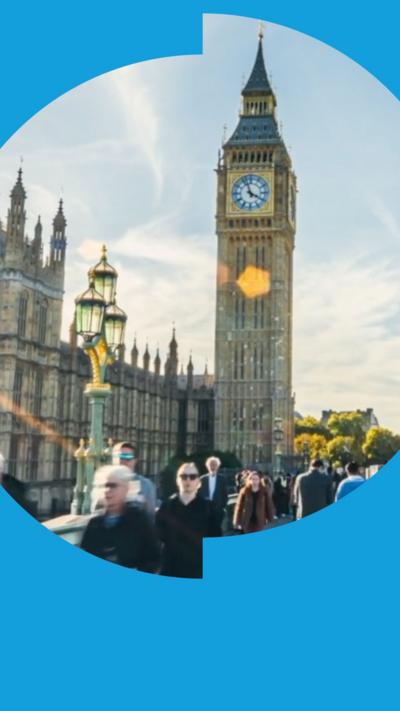 People walk in front of a large clocktower