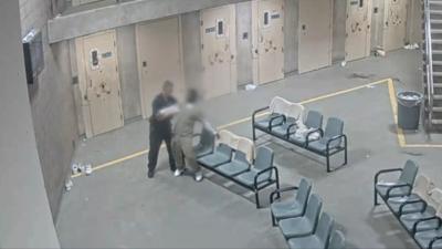 A prisoner officer helps an inmate struggling to stand
