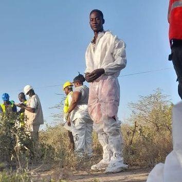 A group of people wearing flimsy white plastic overalls. One of them is looking at the camera