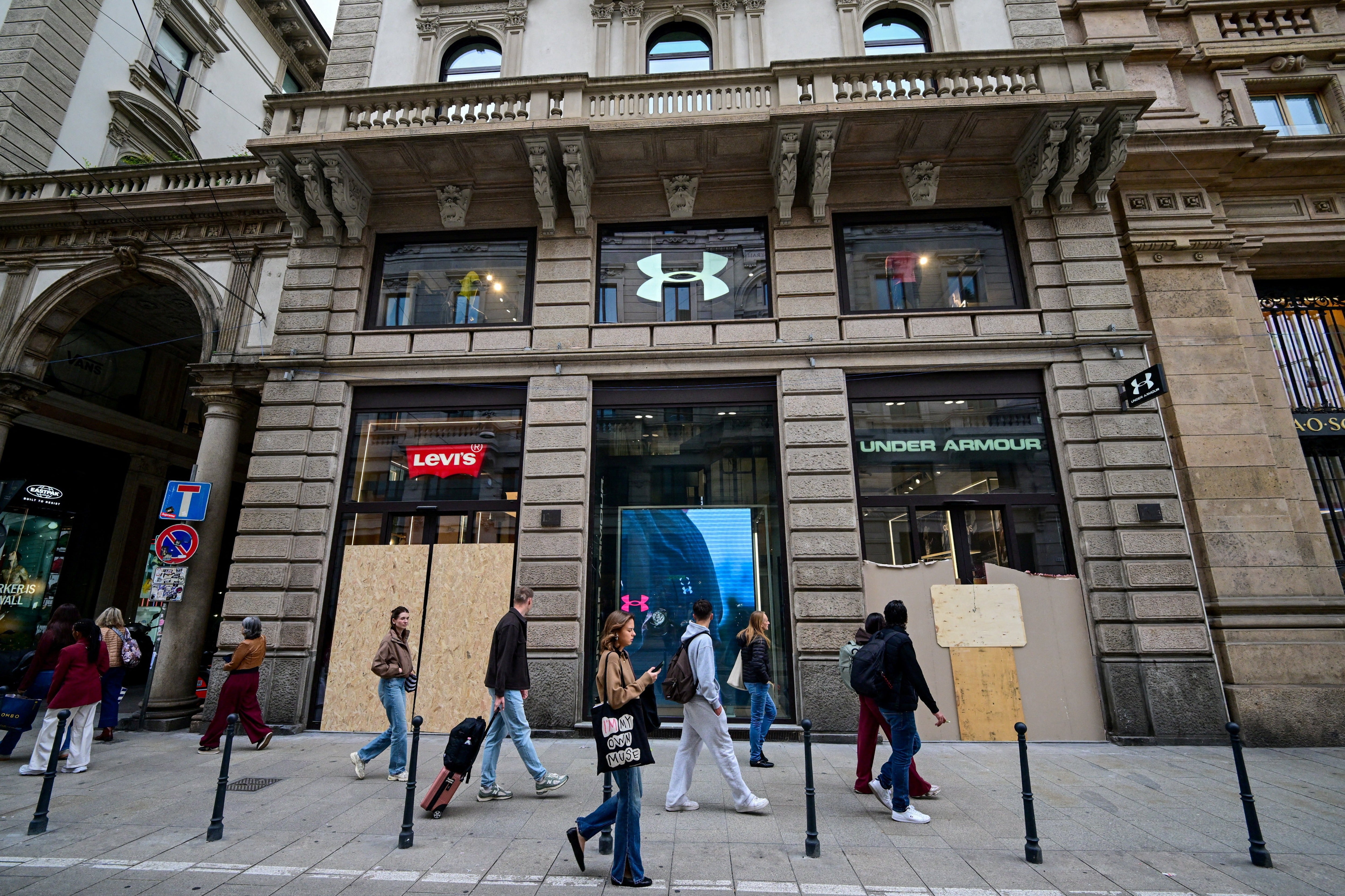 Pedestrians walk past boarded-up Levi's and Under Armour storefronts