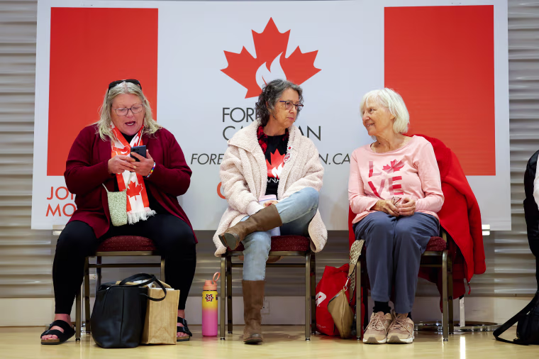 Image: Three women wearing Canadian flag clothes sit together.