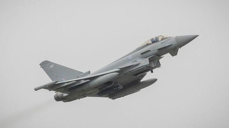 An RAF Typhoon flying in a grey sky