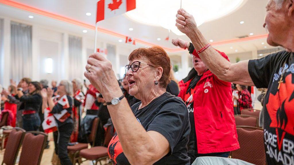 A group of people wave Canadian flags during an event in Edmonton where they have been following the results of a vote on whether or not Alberta should separate from the rest of Canada