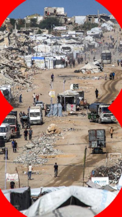 Rubble from destroyed buildings (left), next to multiple white tents, next to buildings (right).