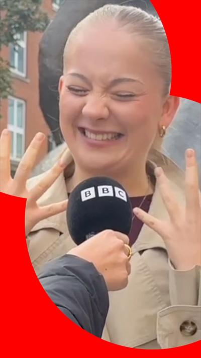 A woman with blonde hair pulls a face
