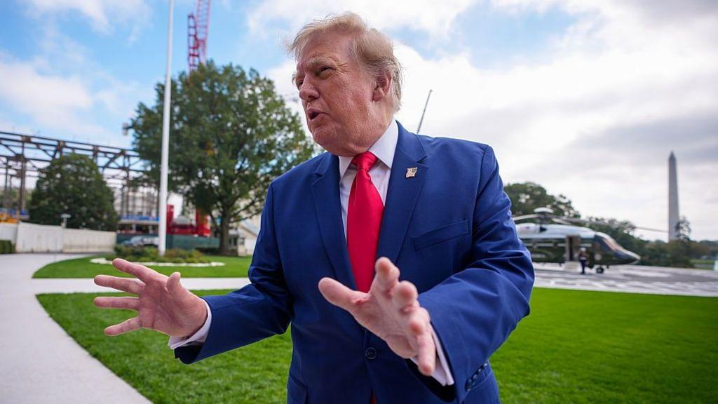 Trump standing and gesturing with his hands as he leaves the White House