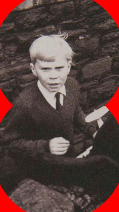 Black and white picture of a young boy in school uniform looking to camera 