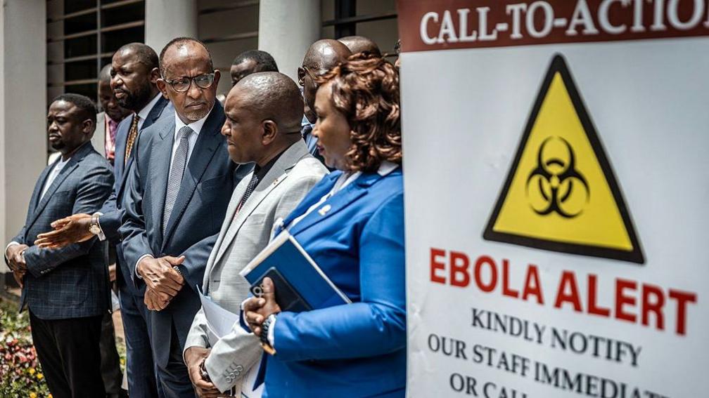 A group of senior government officials including Health Minister Aden Duale, third left, in a dark suit, address the media outside an isolation facility marked with an Ebola alert sign at Nairobi Hospital in Nairobi