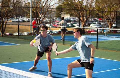 Two people playing pickleball outside