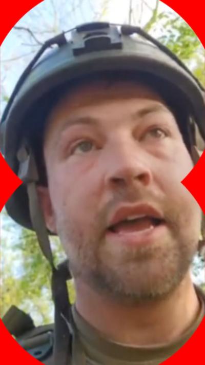 An man is wearing a green helmet with chin straps. He is wearing camouflage clothing and looking up into the distance. He is surrounded by trees. 