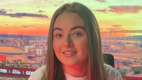 Keeley smiling. She is wearing a pink shirt with the Kappa symbol on it. She has long fair hair.