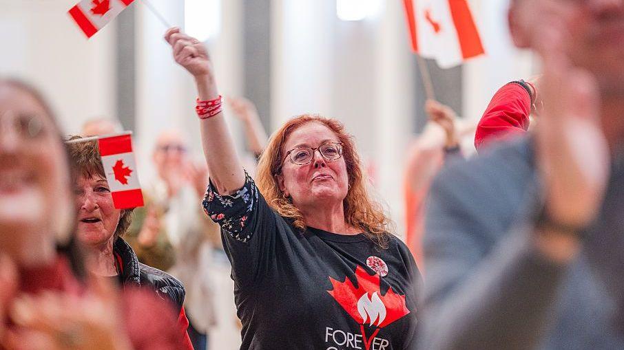 A woman wearing a "Forever Canadian" t-shirt waves a Canadian flag during an event in Edmonton following the province's vote on whether to pursue an independence referendum