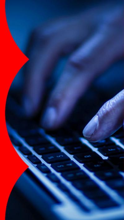 Dark screen with hands typing on a computer laptop