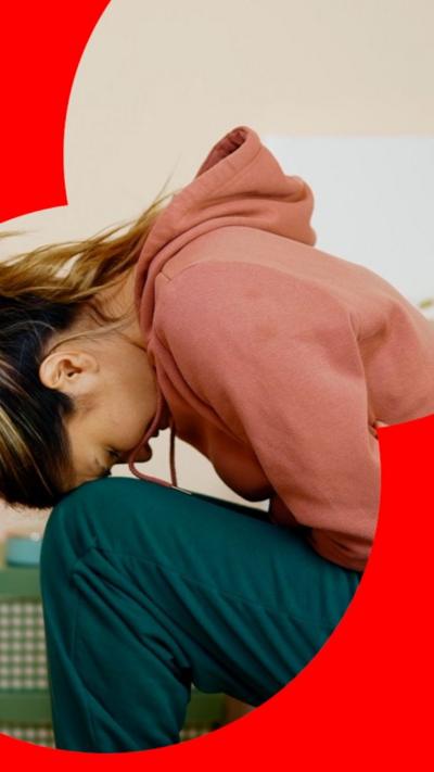 Woman in pink hoodie bent over in pain