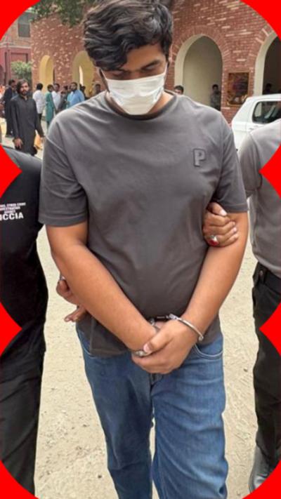 Man in a grey t-shirt and a white face-mask on with handcuffs being led by two other people.