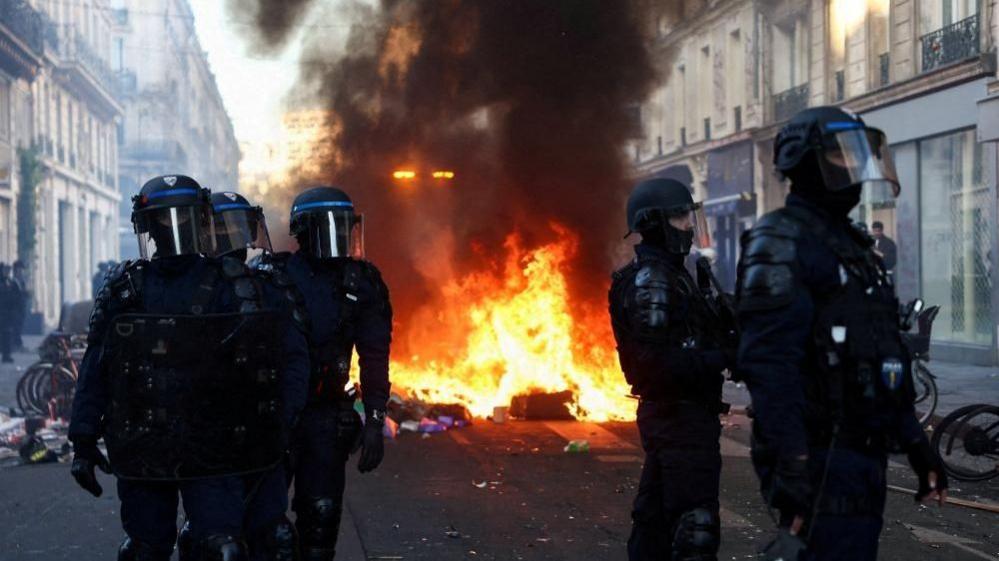 Riot police near a fire in a Paris street
