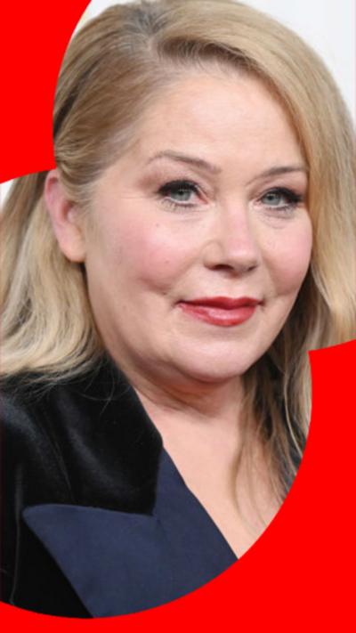 Christina Applegate looks into camera with wavy blonde hair wearing a suit jacket.