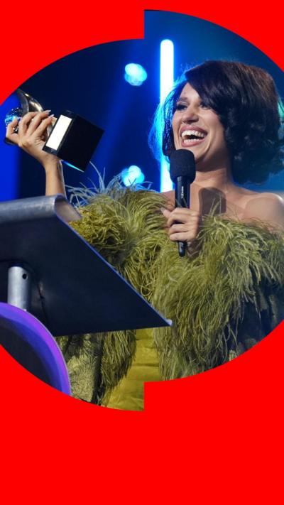 Musician Raye smiles as she looks at the Mercury Prize she has just won at a ceremony.