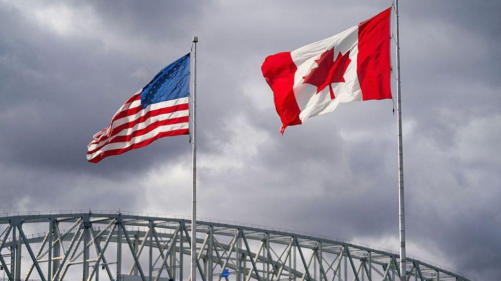The US and Canada flags flutter next to the Blue Water Bridge border crossing in Point Edward, Ontario, on 24 October 2025. 