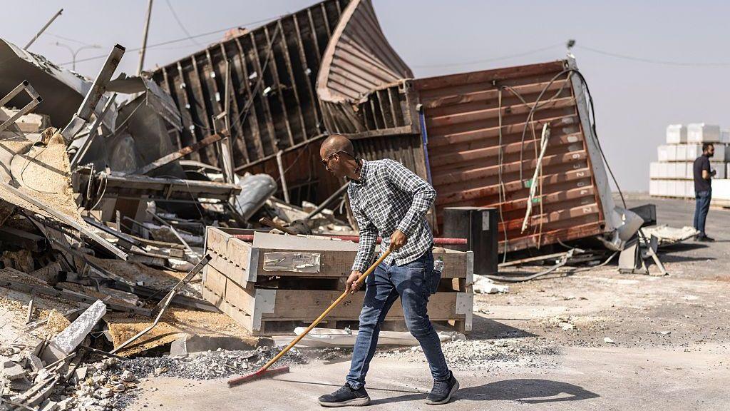 Man sweeps up debris. 