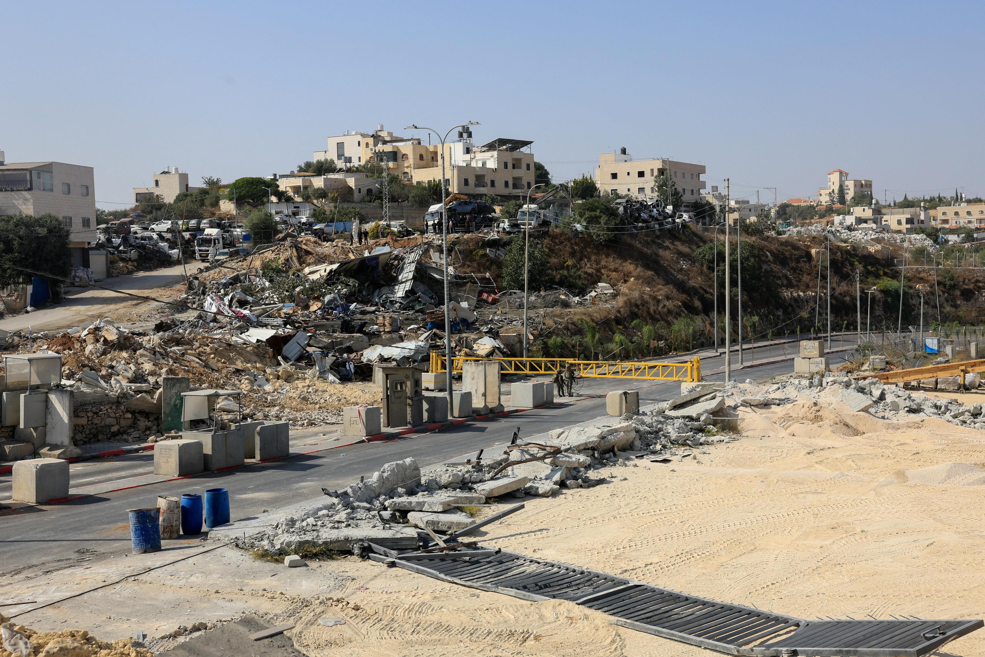 Sandy land around checkpoint. Wreckage in the distance. 