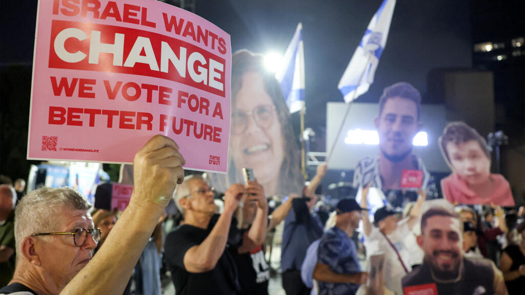 Protesters gather with signs depicting victims during an anti-government demonstration demanding a state commission of enquiry into Hamas' 2023 October attacks ahead of Israel's upcoming election