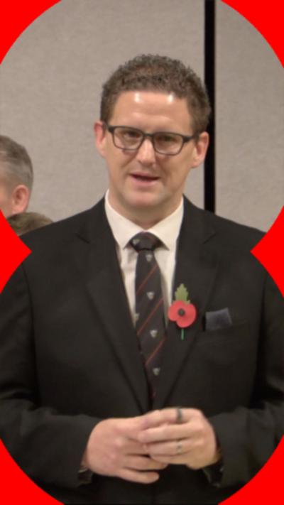 Reform MS Jason O'Connell has short brown hair. He has glasses and is wearing a dark suit and tie. There is a poppy on his left lapel.